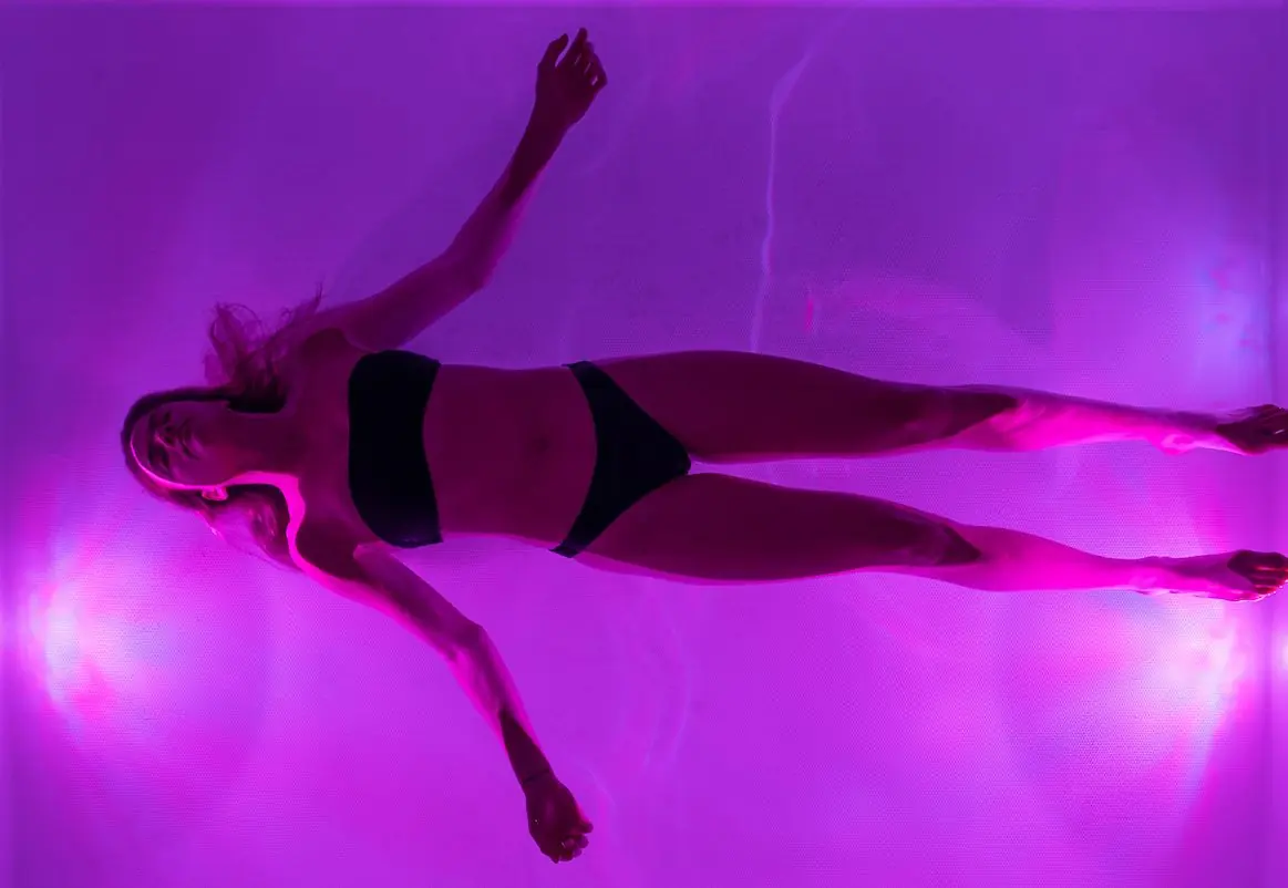 A guest floating in a blue-lit float suite